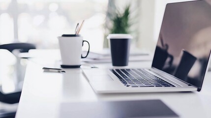 Modern workspace with laptop, coffee, and stationery on a white desk.