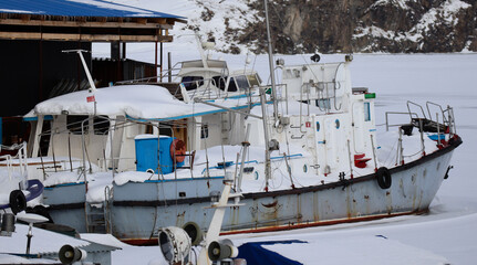 Small ships moored at Ust-Kamenogorsk reservoir. Ships frozen in ice. East kazakhstan region