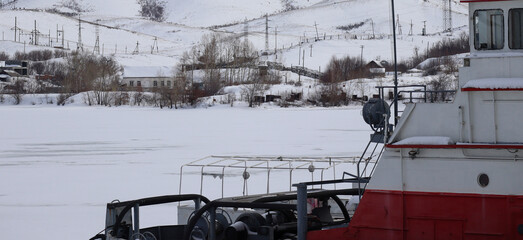 The tugboat moored at Ust-Kamenogorsk reservoir. City suburb. Winter. Frozen reservoir. East Kazakhstan Region