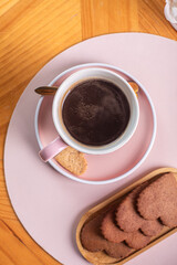 Coffee cup with saucer and cookies on a wooden table, perfect for a cozy afternoon break, showcasing a delightful snack and beverage pairing concept
