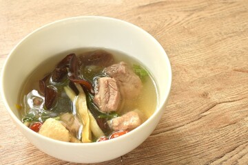 boiled day lily topping tofu with pork bone and ear mushroom in Chinese herb soup on bowl 