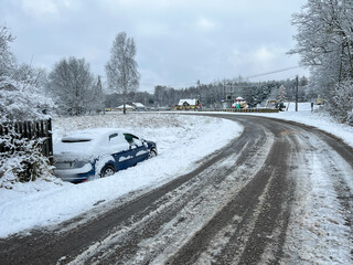 Snowfall causes traffic disruptions. A passenger car skidded and fell off the roadway, stopped in a...