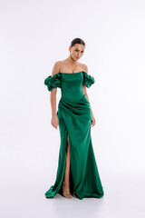 Beautiful brunette girl in a green and emerald evening dress on a white background isolated