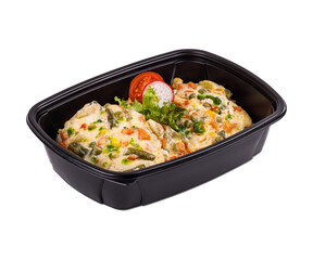 A black plastic container that is filled to the brim with food and vegetables