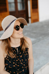 Frau mit Sonnenbrille und Sonnenhut sitzt auf Steinstufen