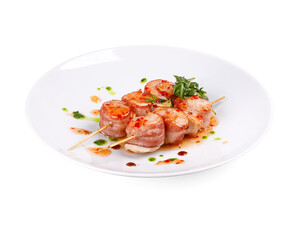 A white plate topped with delicious meat and vegetable skewers