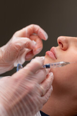 Professional cosmetologist girl makes correction and lip augmentation with filler injection in...