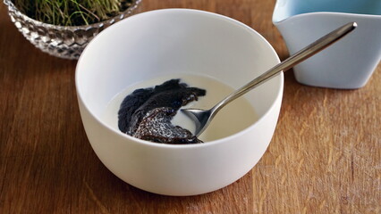 Traditional Finnish Mämmi Dessert– Easter Rye Pudding in a White Ceramic Bowl and easter grass decoration on wooden surface