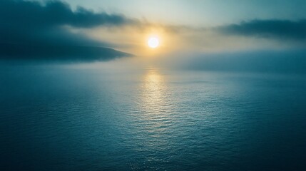 Obraz premium Misty sunrise over calm ocean.