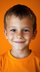 Smiling boy portrait, orange background, studio shot, possible use for child development or education stock