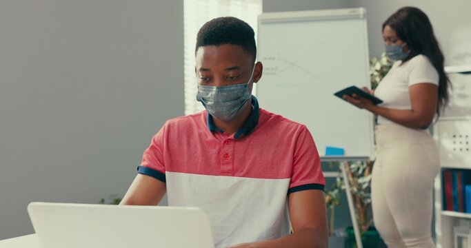 A busy woman stands at the blackboard holding a tablet, searches for the right graphic, prepares a diagram, a man sits at desk entering the data into the system needed to create the diagram