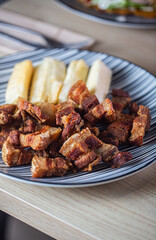 Deliciously grilled pork served with fried plantains on a striped plate, showcasing a vibrant culinary experience and a healthy eating concept
