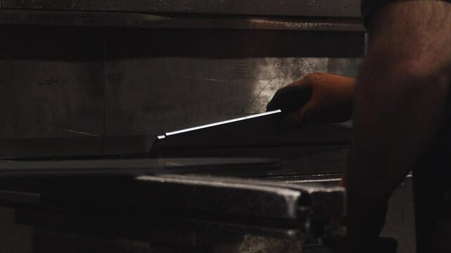 A person is holding a knife and standing in front of a stove. The knife is on a counter next to a pan