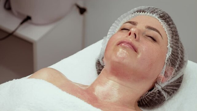 Woman client relaxing during procedure in skin studio, enhancing natural beauty. Skin studio focusing on professional care and rejuvenation treatments for glowing results. Cosmetic dermatology clinic