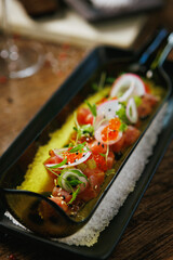 Tuna tartare with avocado puree, radish, and salmon roe. Garnished with microgreens and served in a modern black dish. Fresh and vibrant appetizer in contemporary gourmet cuisine