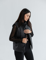 Portrait of a cute girl model in a black vest and pants on a white background in the studio