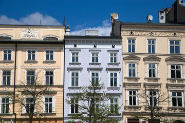 Row of colorful townhouses in Krakow, Poland, under a partly cloudy blue sky.