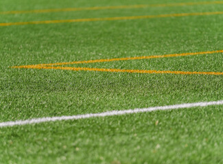 Green synthetic grass with white and orange lines for sports field activities