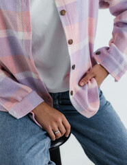 Portrait of a cute girl model in a pink checkered shirt and jeans in the studio on a white...