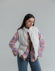 Portrait of a cute girl model in a pink checkered shirt and jeans in the studio on a white...