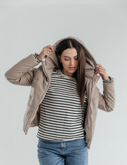 Portrait of a cute girl model in a leather beige jacket and jeans on a white background isolated