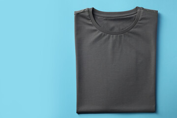 One blank t-shirt on light blue background, top view. Mockup for design