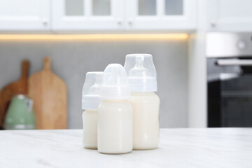 Feeding bottles with milk on white table indoors
