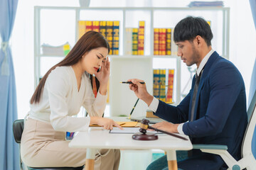 Male lawyer discussing contract documents, business woman sitting at advice table, legal consulting service and a scale with a judge's hammer placed next to it.