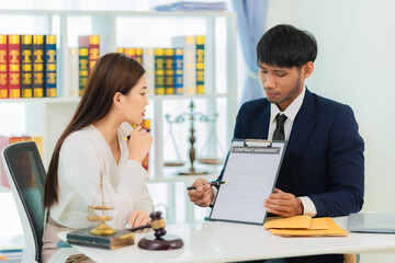 Male lawyer discussing contract documents, business woman sitting at advice table, legal consulting service and a scale with a judge's hammer placed next to it.