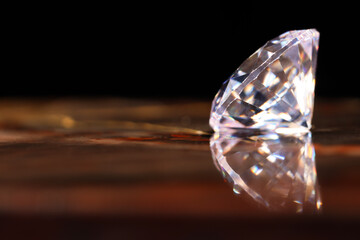 Beautiful shiny gemstone on mirror surface against dark background, closeup. Space for text