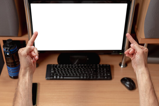 Closeup of young man using computer and showing middle fingers. Man's expressive gestures towards white screen on computer monitor, viewed from behind