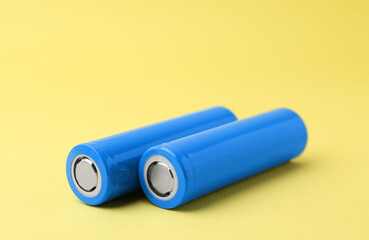 Two AA cell batteries on yellow background, closeup. Space for text