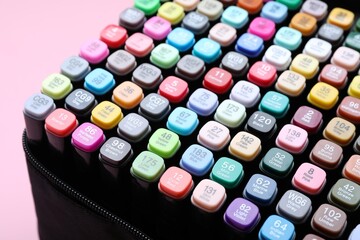 Many colorful markers in bag on pink background, closeup