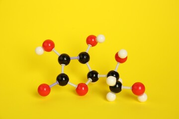 Molecule of vitamin C on yellow background. Chemical model