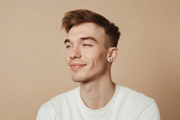 Smiling young man looking away wearing white t-shirt on beige background