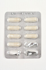 A close-up shot of a blister pack containing white capsules, some of which have been partially used