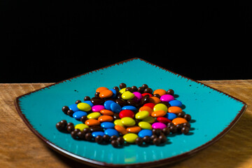 Close-up of colorful chocolate candies on a vibrant turquoise plate, perfect for food and confectionery themes