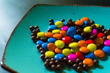 Close-up of colorful chocolate candies on a vibrant turquoise plate, perfect for food and confectionery themes
