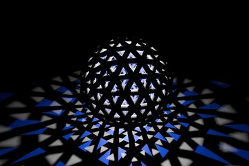 Round sphere consisting of massive bars, with lights inside, casts white and blue triangular shadows to the outside. 