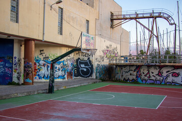 Empty basketball court with graffiti in crime-ridden districts where gangs rule, highlighting time spent on sports activities.