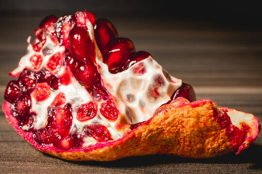 O peace of a Pomegrenade with the seeds inside, on a wooden background.