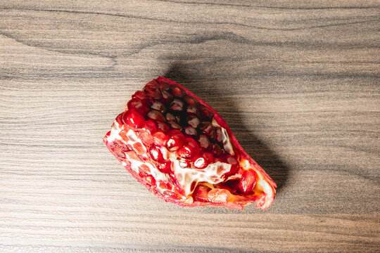 O peace of a Pomegrenade with the seeds inside, on a wooden background.