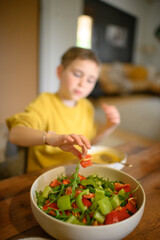 A young boy enjoys a healthy meal with his family, eating soup and salad with great appetite. The scene reflects wholesome nutrition, warmth, and togetherness at the dining table.