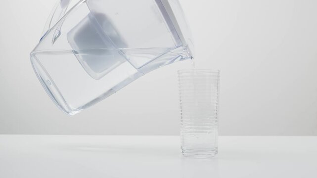 A close-up image of water being poured from a pitcher into a tall glass, showcasing cleanliness and hydration.