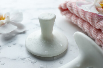 Wet spa stones, orchid flowers and towel on white marble table, closeup