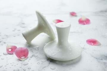 Wet spa stones and petals on white marble table, closeup