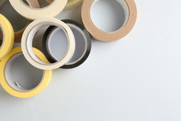 Rolls of different adhesive tapes on white background, flat lay. Space for text