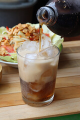 Cola soft drink with ice cubes and papaya salad spicy Thai food
