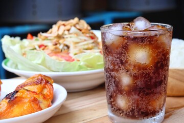Cola soft drink with ice cubes and papaya salad spicy Thai food