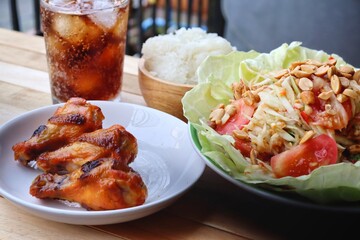 Cola soft drink with ice cubes and papaya salad spicy Thai food